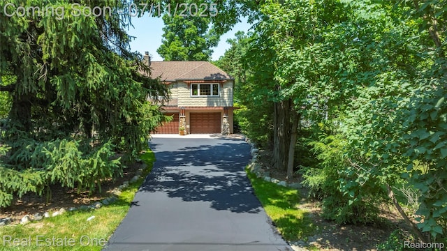 25740 Farmbrook Rd, Southfield, MI 48034 - view of property hidden behind natural elements featuring stone siding, driveway, a garage, and a chimney
