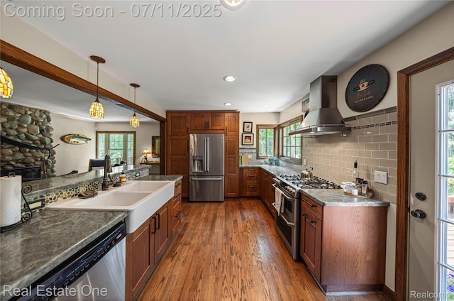25740 Farmbrook Rd, Southfield, MI 48034 - kitchen with appliances with stainless steel finishes, wall chimney range hood, wood finished floors, decorative backsplash, and pendant lighting