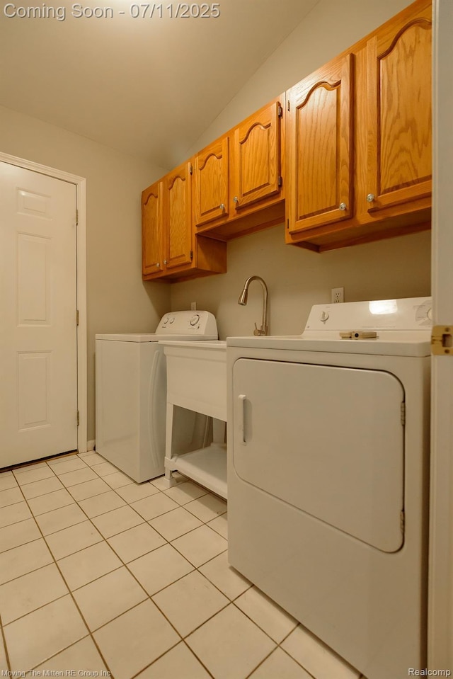 61001 Evergreen Ct, South Lyon, MI 48178 - laundry area featuring washing machine and clothes dryer, cabinet space, and light tile patterned floors