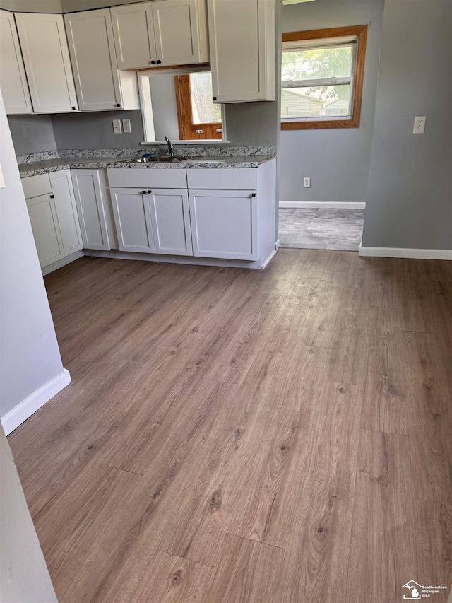 6114 Hazel St, Taylor, MI 48180 - kitchen featuring light wood finished floors, light stone countertops, and white cabinetry
