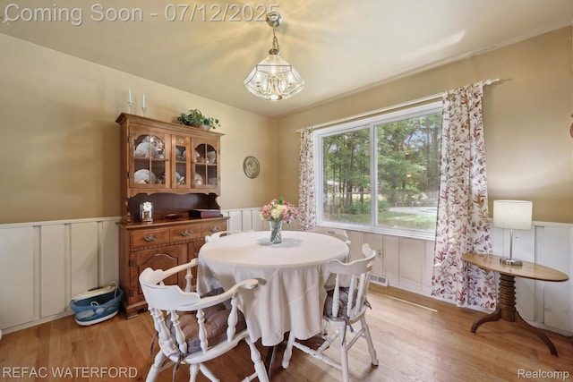 11857 Ely Rd, Davisburg, MI 48350 - dining area with light wood-style flooring, a wainscoted wall, a decorative wall, and a chandelier