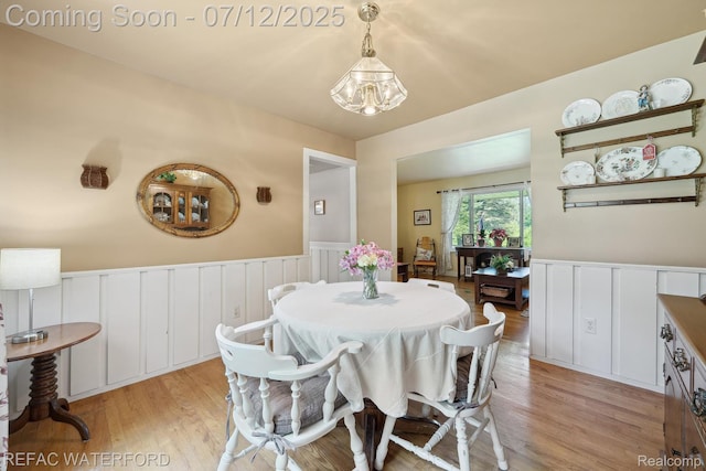 11857 Ely Rd, Davisburg, MI 48350 - dining room with light wood-style floors, a decorative wall, a wainscoted wall, and a chandelier