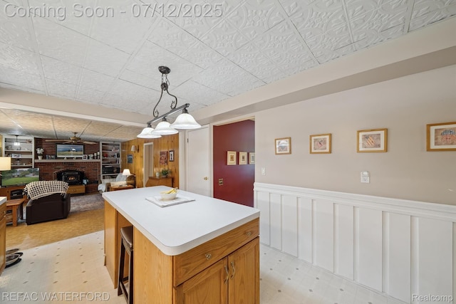 11857 Ely Rd, Davisburg, MI 48350 - kitchen featuring a fireplace, a center island, light countertops, a wainscoted wall, and open floor plan