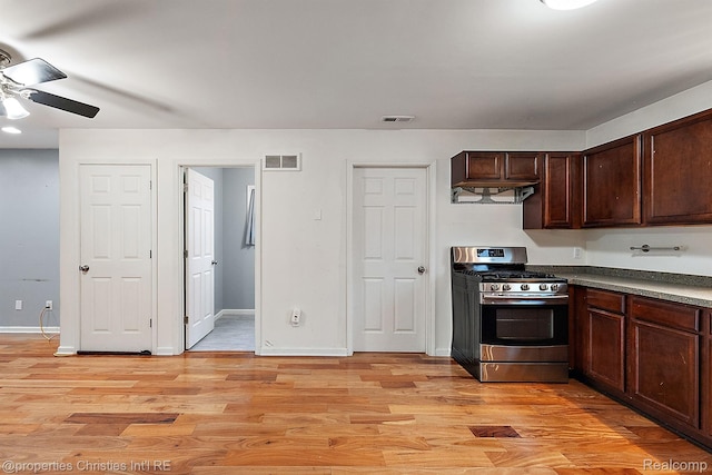 8873 Lagoon Dr, Brighton, MI 48116 - kitchen with gas range, light wood-type flooring, ceiling fan, dark countertops, and dark brown cabinetry