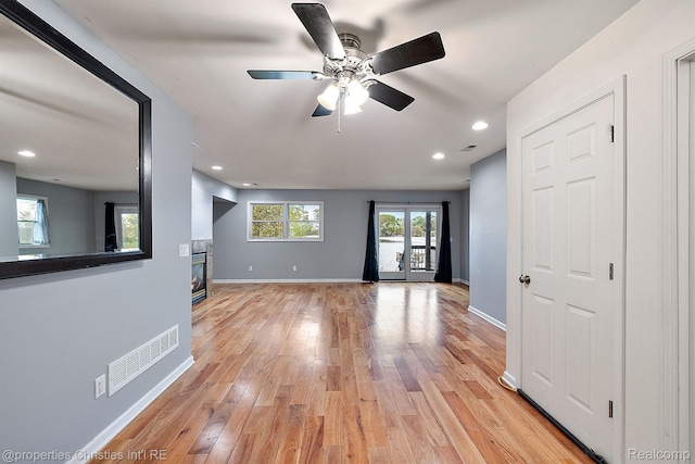 8873 Lagoon Dr, Brighton, MI 48116 - unfurnished living room featuring a glass covered fireplace, light wood-type flooring, ceiling fan, and recessed lighting