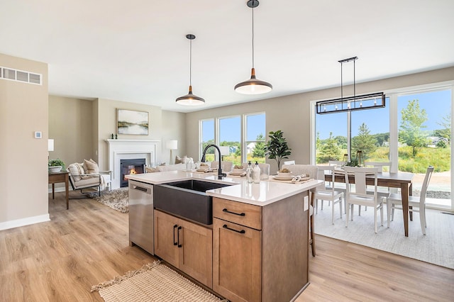 9088 N 34th St, Richland, MI 49083 - kitchen featuring dishwasher, light wood finished floors, a glass covered fireplace, light countertops, and a kitchen island with sink