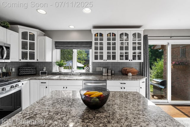 4317 Vassar Dr, Troy, MI 48085 - kitchen featuring stainless steel appliances, glass insert cabinets, dark stone counters, white cabinetry, and recessed lighting