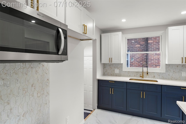 19777 Santa Rosa Dr, Detroit, MI 48221 - kitchen with stainless steel microwave, blue cabinetry, white cabinets, light marble finish floors, and light countertops
