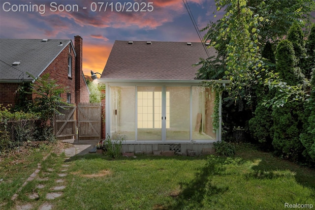 19777 Santa Rosa Dr, Detroit, MI 48221 - back of house at dusk with a sunroom, a lawn, and a shingled roof