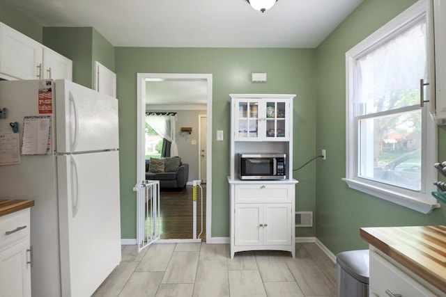 29687 Westfield St, Livonia, MI 48150 - kitchen with freestanding refrigerator, stainless steel microwave, white cabinets, and butcher block counters