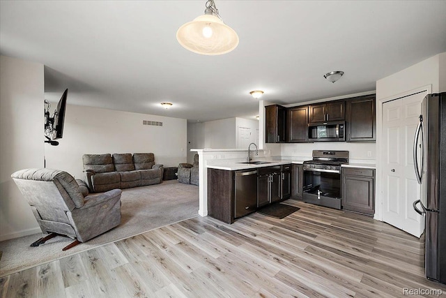 58565 Westmoore Cir, New Haven, MI 48048 - kitchen featuring appliances with stainless steel finishes, open floor plan, dark brown cabinets, light wood-style flooring, and light countertops