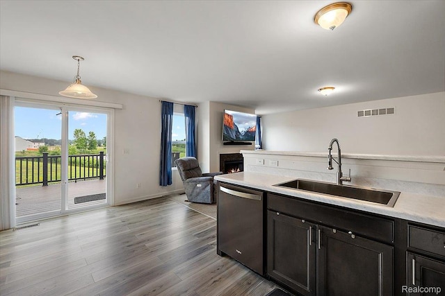 58565 Westmoore Cir, New Haven, MI 48048 - kitchen with dishwasher, light countertops, a warm lit fireplace, light wood-style flooring, and open floor plan