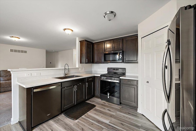 58565 Westmoore Cir, New Haven, MI 48048 - kitchen with appliances with stainless steel finishes, light wood-type flooring, a peninsula, light countertops, and dark brown cabinets