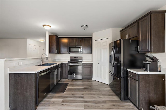 58565 Westmoore Cir, New Haven, MI 48048 - kitchen with appliances with stainless steel finishes, dark brown cabinetry, a peninsula, light countertops, and light wood-style floors