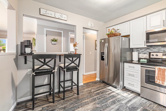 1820 W Longmeadow Rd, Trenton, MI 48183 - kitchen with stainless steel appliances, dark wood-type flooring, white cabinets, decorative backsplash, and dark countertops
