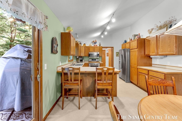 15071 Steves Dr, Grand Haven, MI 49417 - kitchen with appliances with stainless steel finishes, a peninsula, light countertops, a kitchen bar, and track lighting