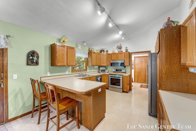 15071 Steves Dr, Grand Haven, MI 49417 - kitchen featuring stainless steel appliances, track lighting, a peninsula, brown cabinets, and light countertops
