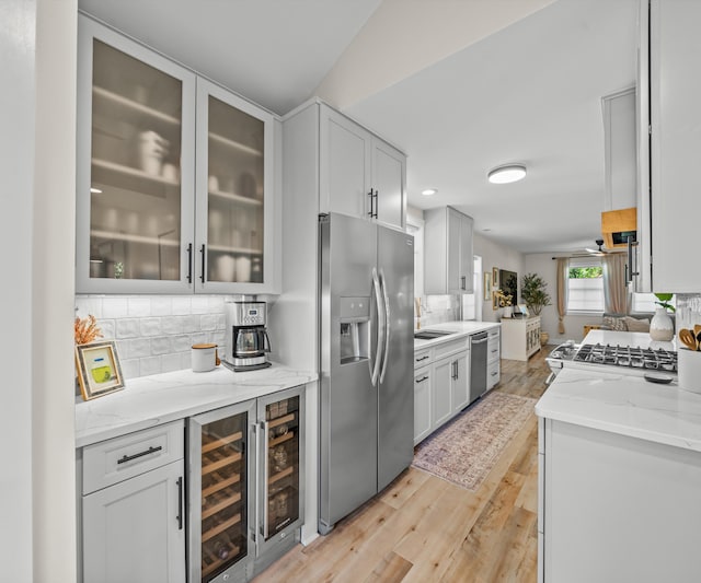 820 Barton Dr, Ann Arbor, MI 48105 - kitchen featuring appliances with stainless steel finishes, backsplash, beverage cooler, light wood-type flooring, and light stone counters