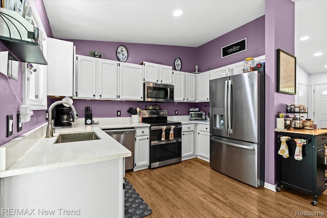 9125 Mandon Rd, White Lake, MI 48386 - kitchen featuring stainless steel appliances, white cabinetry, wood finished floors, light stone countertops, and recessed lighting