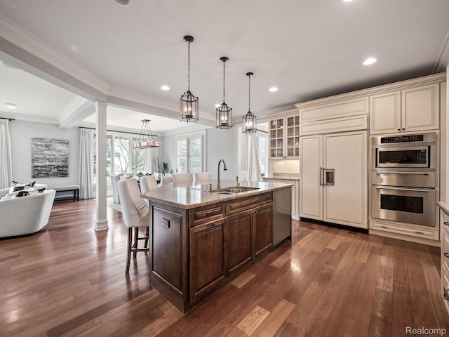 1200 Shipman Blvd, Birmingham, MI 48009 - kitchen featuring appliances with stainless steel finishes, dark wood finished floors, ornate columns, a breakfast bar, and open floor plan