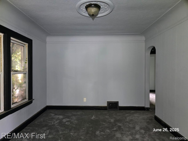 9379 Manor St, Detroit, MI 48204 - empty room featuring arched walkways, a textured ceiling, and carpet