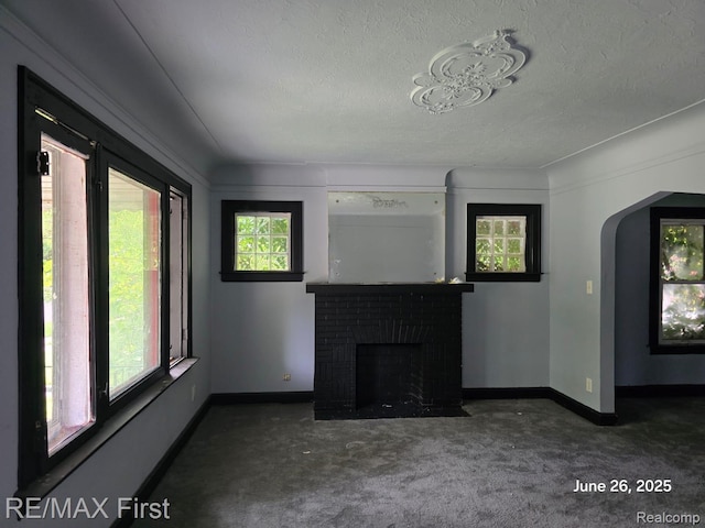9379 Manor St, Detroit, MI 48204 - unfurnished living room featuring carpet, a textured ceiling, a fireplace, and arched walkways