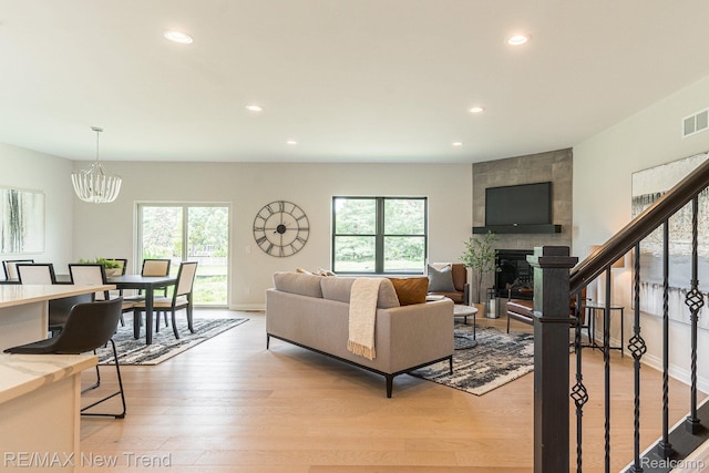 3184 Roma Ct, Wixom, MI 48393 - living room featuring recessed lighting, a fireplace, a chandelier, light wood-style floors, and stairway