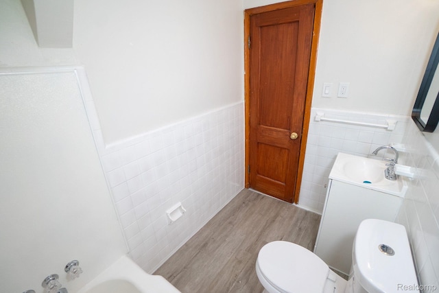 19145 Strasburg St, Detroit, MI 48205 - full bathroom featuring tile walls, wainscoting, wood finished floors, vanity, and a tub