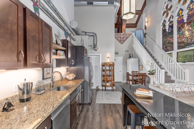 253 Prospect Ave NE Unit 309, Grand Rapids, MI 49503 - kitchen with a high ceiling, appliances with stainless steel finishes, dark wood finished floors, light stone countertops, and open shelves