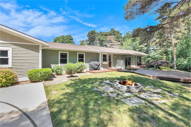 5920 Iris Rd, Ludington, MI 49431 - rear view of house featuring an outdoor fire pit, a deck, and a lawn