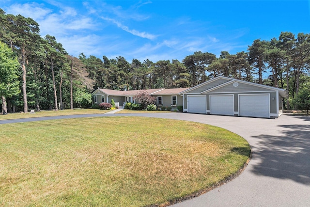 5920 Iris Rd, Ludington, MI 49431 - ranch-style home with asphalt driveway, a garage, and a front lawn