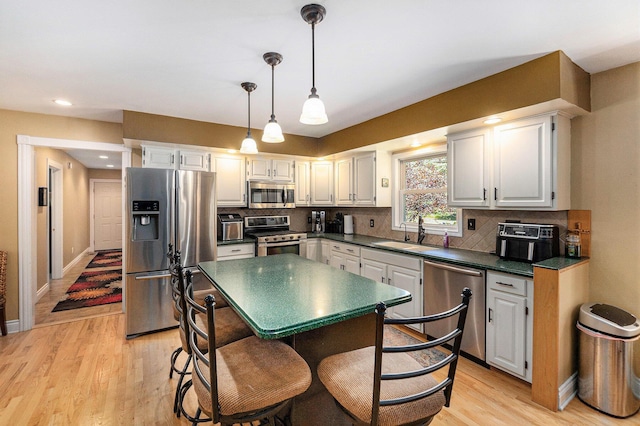5920 Iris Rd, Ludington, MI 49431 - kitchen with stainless steel appliances, light wood-style floors, dark countertops, decorative backsplash, and white cabinetry