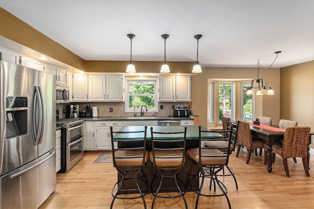 5920 Iris Rd, Ludington, MI 49431 - kitchen featuring appliances with stainless steel finishes, light wood-style floors, tasteful backsplash, and healthy amount of natural light