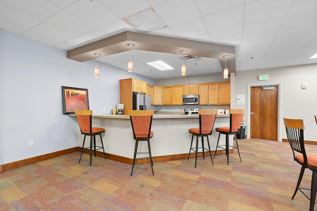 125 S Kalamazoo Mall Unit 603, Kalamazoo, MI 49007 - kitchen featuring stainless steel appliances, light carpet, a drop ceiling, a breakfast bar area, and a peninsula