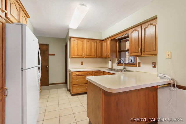 1838 Kings Ct, Muskegon, MI 49445 - kitchen featuring freestanding refrigerator, a peninsula, light countertops, light tile patterned floors, and brown cabinetry
