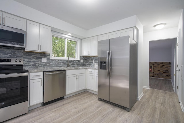 1796 Norfolk Ave, Ypsilanti, MI 48198 - kitchen with stainless steel appliances, light wood-type flooring, light stone counters, white cabinets, and decorative backsplash