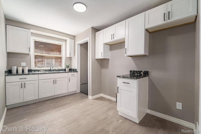 6031 Grandville Ave, Dearborn, MI 48228 - kitchen featuring light wood-style flooring, white cabinetry, and dark stone counters