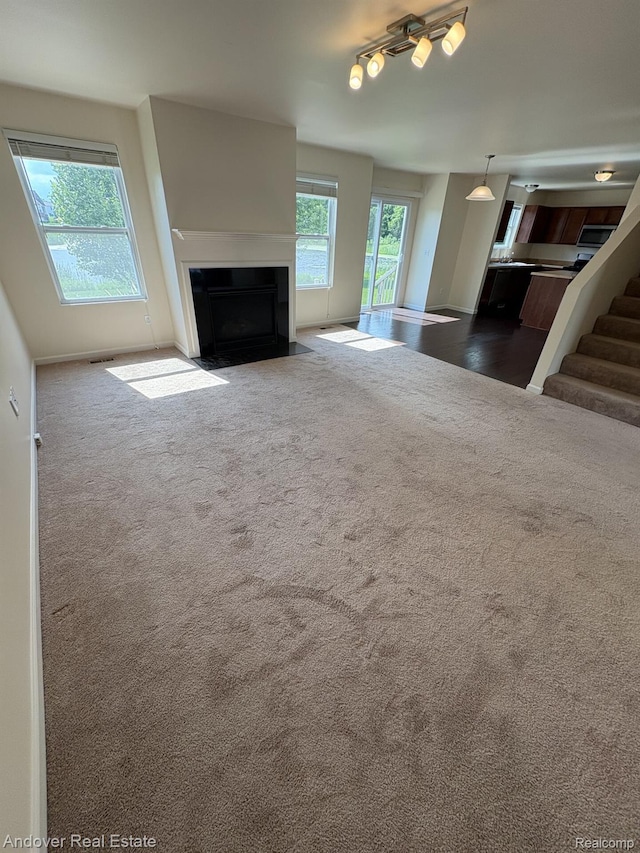 8213 Bayberry Ct, Dexter, MI 48130 - unfurnished living room with carpet floors, a fireplace with flush hearth, and stairway