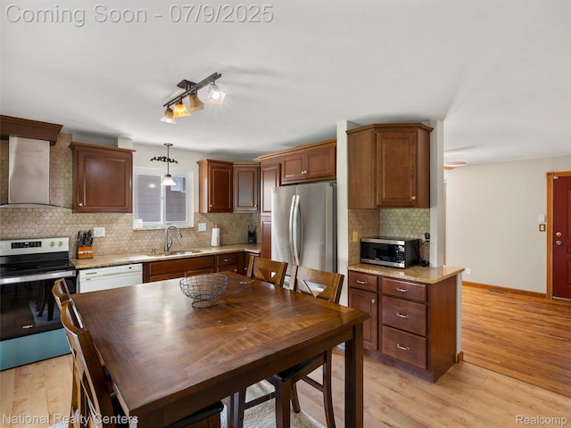 2553 Koper Dr, Macomb, MI 48310 - kitchen with stainless steel appliances, wall chimney range hood, decorative backsplash, light wood-type flooring, and hanging light fixtures