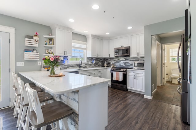 10501 Somerset Rd, Cement City, MI 49233 - kitchen featuring stainless steel appliances, a peninsula, white cabinetry, decorative backsplash, and recessed lighting