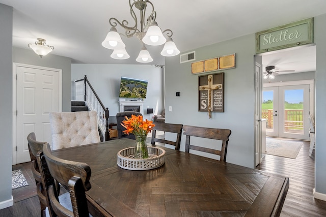 10501 Somerset Rd, Cement City, MI 49233 - dining area featuring stairway, a chandelier, a ceiling fan, a fireplace, and wood finished floors