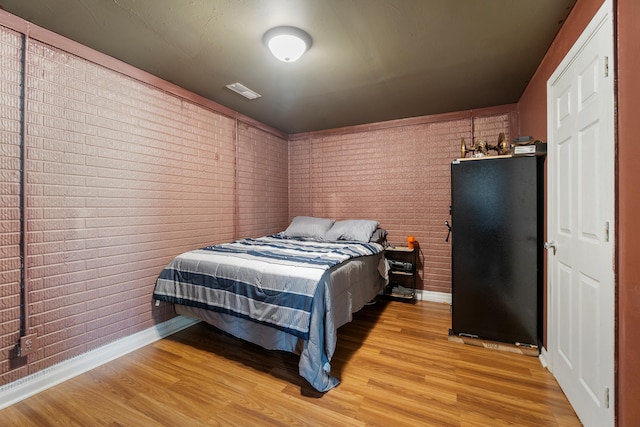 10501 Somerset Rd, Cement City, MI 49233 - bedroom with brick wall and light wood-style flooring