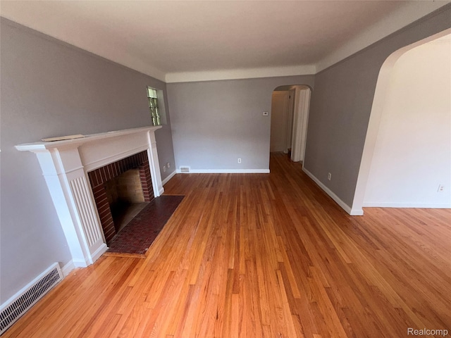 5565 Oldtown St, Detroit, MI 48224 - unfurnished living room featuring arched walkways, wood finished floors, and a fireplace