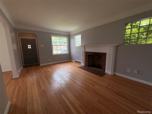 5565 Oldtown St, Detroit, MI 48224 - unfurnished living room with light wood-type flooring, arched walkways, and a brick fireplace