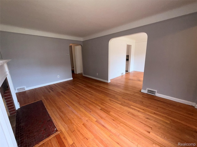 5565 Oldtown St, Detroit, MI 48224 - unfurnished living room with arched walkways, wood finished floors, and a brick fireplace