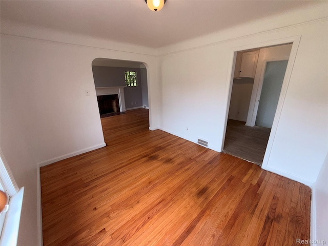 5565 Oldtown St, Detroit, MI 48224 - unfurnished room featuring arched walkways, light wood-style floors, and a fireplace with flush hearth