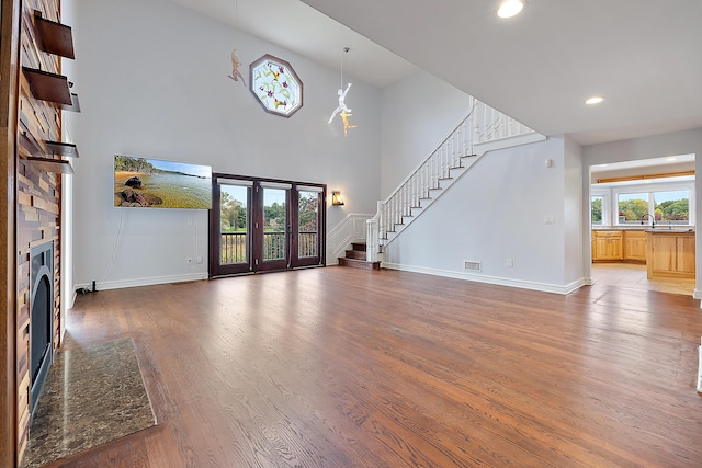 4700 Raap Rd, Bruce, MI 48065 - unfurnished living room with stairway, a fireplace, light wood finished floors, recessed lighting, and a high ceiling