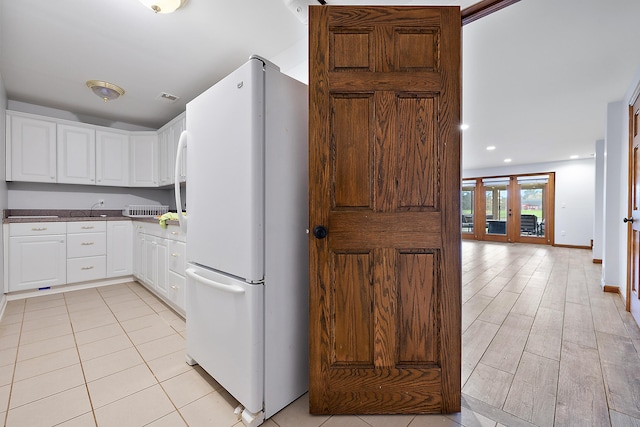 4700 Raap Rd, Bruce, MI 48065 - kitchen with freestanding refrigerator, white cabinetry, dark countertops, and light tile patterned floors