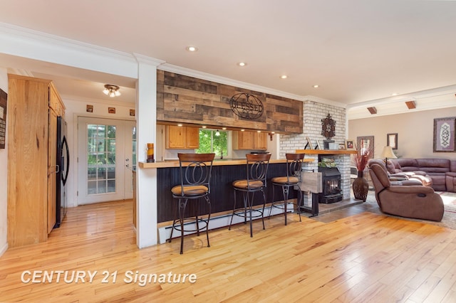 7320 N River Rd, Freeland, MI 48623 - kitchen featuring crown molding, a baseboard radiator, freestanding refrigerator, light wood-style flooring, and a breakfast bar area