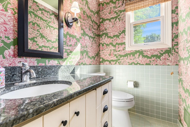 1818 Greenbriar Dr, Portage, MI 49024 - bathroom with wallpapered walls, vanity, wainscoting, tile walls, and tile patterned flooring